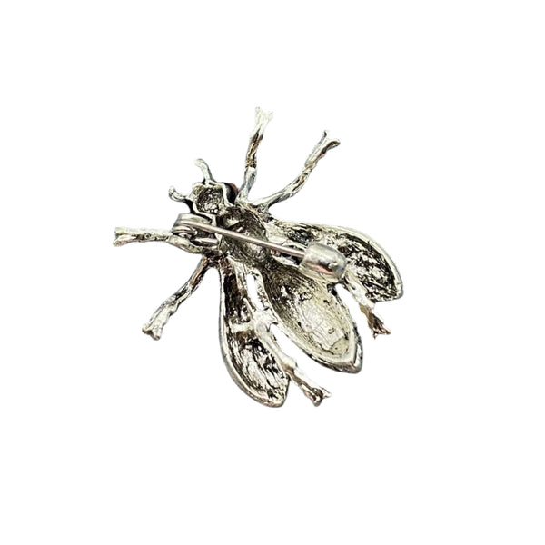 silver metal honeybee brooch with enameled white wings, black and yellow enameled thorax and abdomen, and small red jeweled eyes. Shown from back