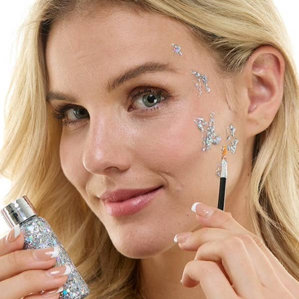 Woman applying glittery silver makeup with a brush and bottle