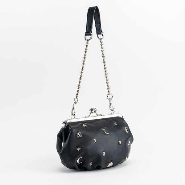 black textured faux leather purse with silver metal kiss lock and silver metal stars, crescent moons, and sun embellishments. Attached is an 11" chain link and faux leather shoulder strap. Shown from side