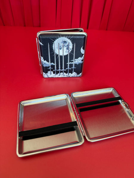 Cigarette case with six of swords tarot card celestial black and white design featuring a moon and six swords against clouds. Shown both open and closed on a red velvet background