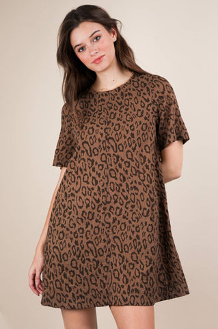 Model wearing a brown leopard print short sleeved a-line mini dress with a rounded collar and side seam pockets. Shown from the front