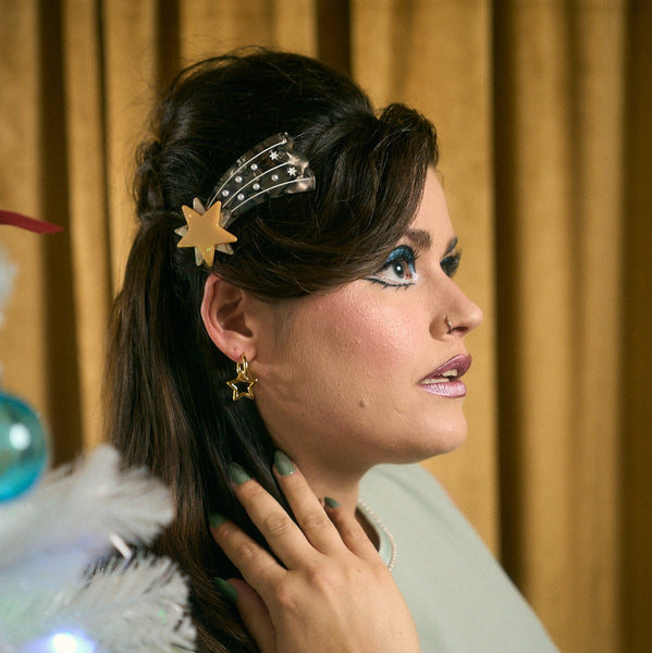 french style hair clip made of plant-based acetate in the shape of a shooting star with metallic gold and marbled gold star & marbled blue trail with white pearls. Shown worn by model wearing updo 