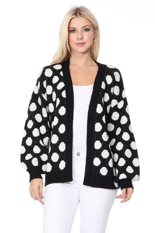 Model wearing an oversized open front cardigan in a white and black polka dot pattern with ribbed cuffs and bottom hem