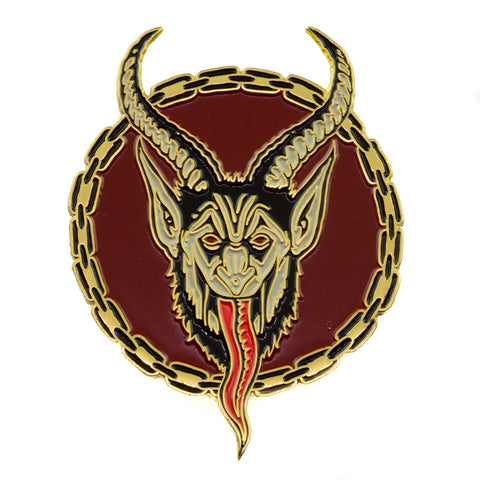 face of Krampus, the Christmas Devil, depicted on a circular gold metal enamel pin