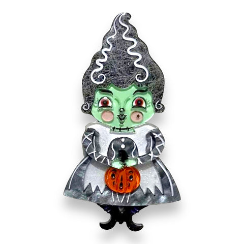 layered acrylic resin brooch of Bride of Frankenstein style cartoon holding a pumpkin