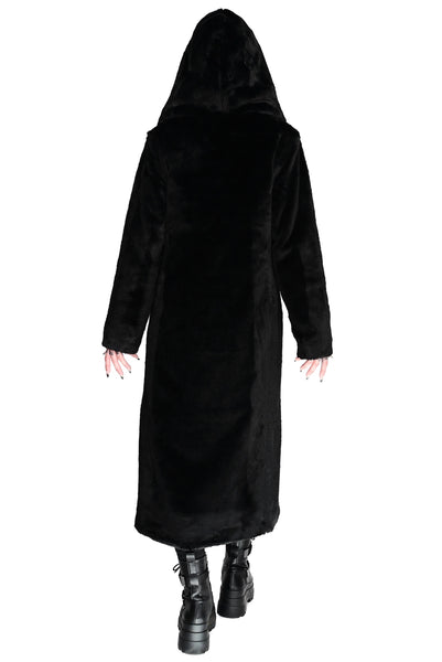 model wearing a black faux fur coat with wide lapel and oversized faux fur lined hood. Coat has double black plastic button closure and side seam pockets. Shown from back with hood up