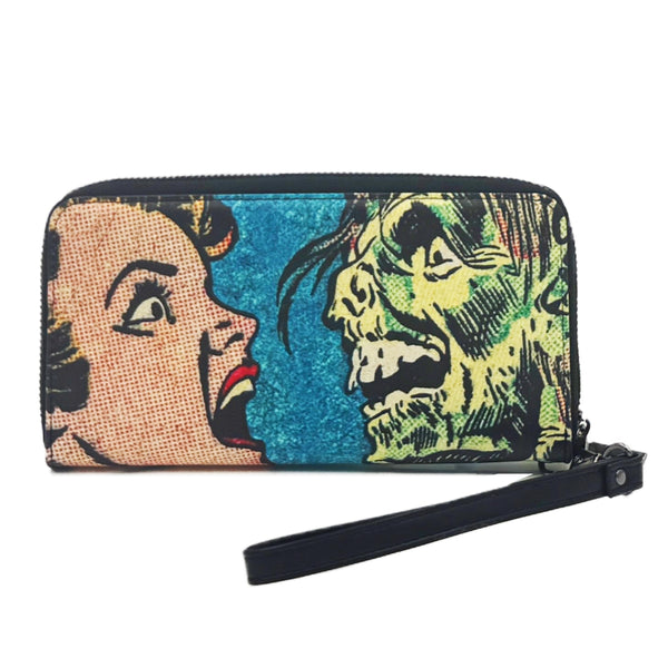 faux leather wristlet wallet with a printed Ben-Day woman's face and green monster design on a blue background shown with faux leather black wrist strap