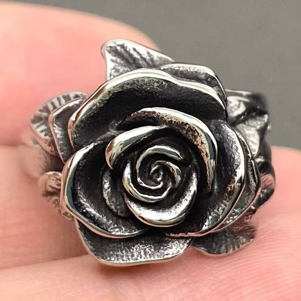 silver stainless steel ring in the shape of a blossoming camellia flower and its leaves. Shown held in close up
