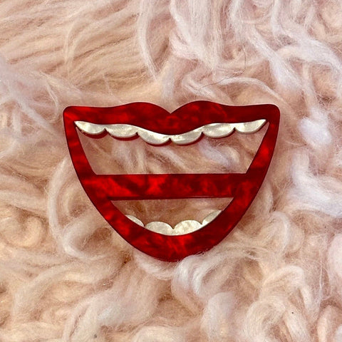 layered acrylic pearly white and red big mouth shaped scarf slide on pink fuzzy background
