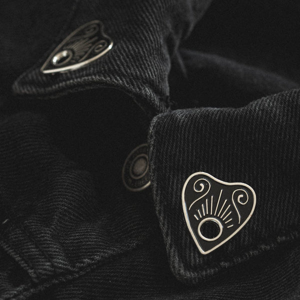 Planchette with black details enameled silver metal clutch-back pin set to fit on collar points shown on collar of black denim jacket