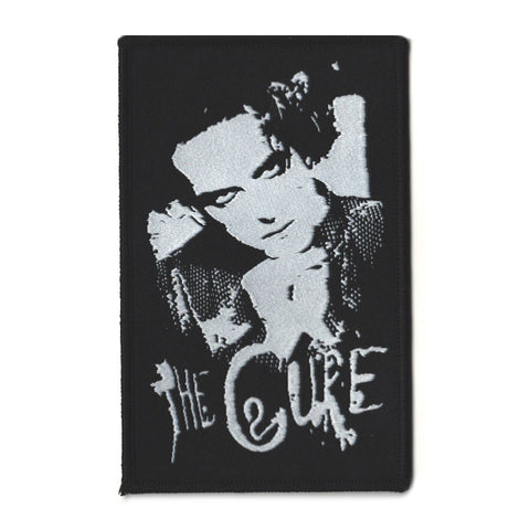 black rectangular patch with logo for The Cure and portrait of Robert Smith shown in grey
