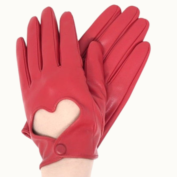 A pair of cherry red faux leather wrist-length gloves with a heart-shaped cutout on the back of the hand and single snap closure. Shown worn by model