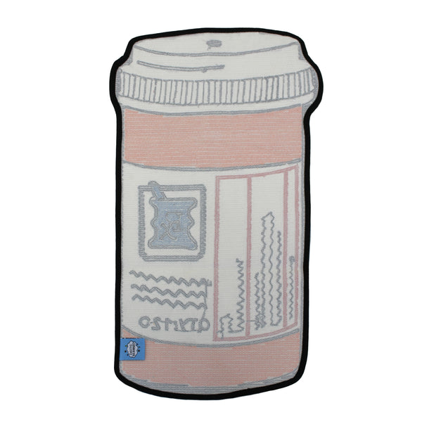 A tufted rug shaped like an orange prescription pill bottle with a white label, black border, and blue Rx symbol, shown from the back on a plain white background. Displays branded label and rubber non-slip backing