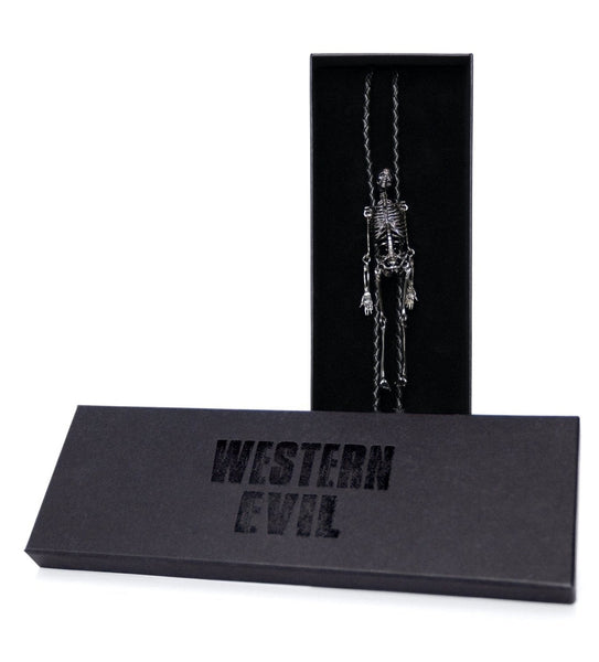 Black braided faux leather bolo tie with black metal tips and slide made of detailed gunmetal finish metal skeleton with articulated joints and head. Shown in black branded card stock gift box
