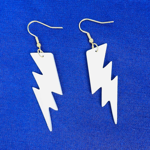 laser cut white acrylic lightning bolt dangle earrings on a blue background