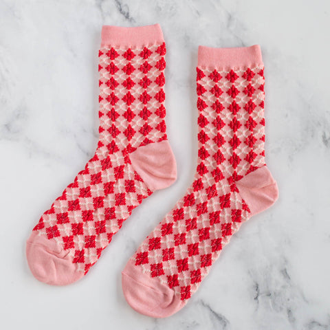 cotton socks in light pink with ribbed cuffs and a red & white argyle knit-in pattern. Shown flat