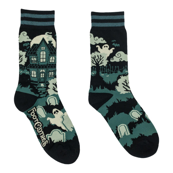 Pair of cotton blend socks in black with teal and black striped cuffs and solid black toes/heels with all-over design of haunted house surrounded by clouds and graveyard with ghosts. Shown flat