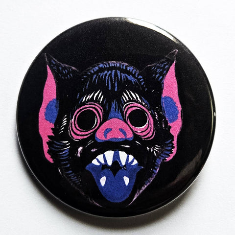 1.25 round pinback button with a stylized bat mask design in purple, pink, and white on a black background