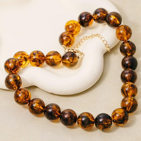 Brown amber translucent marbled round beaded necklace with gold extender chain shown flat