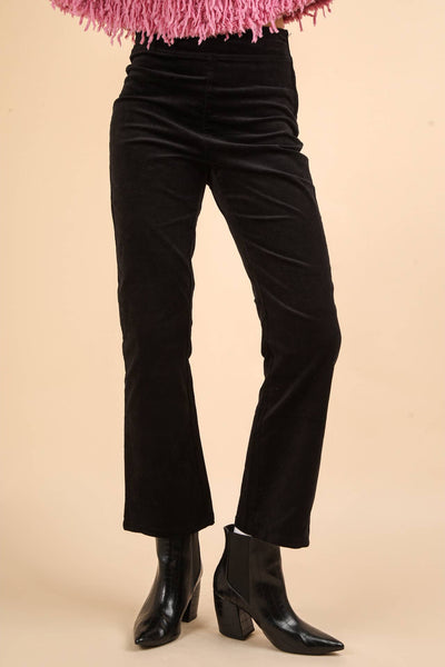 model wearing high-waisted black velvet pants with bootcut style legs, back pockets, and side zip closure. Shown from front