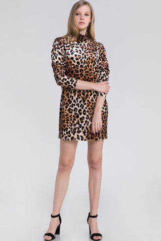 Woman wearing a leopard print velvet shift dress with mock neck, slightly puffed shoulders, bubble sleeves, and above the knee skirt on a white background. Shown from front