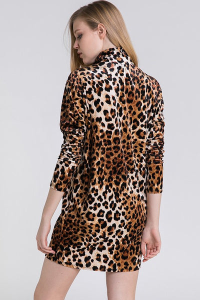 Woman wearing a leopard print velvet shift dress with mock neck, slightly puffed shoulders, bubble sleeves, and above the knee skirt on a white background. Shown from back