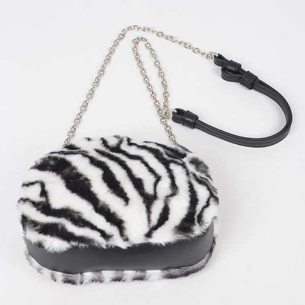 Zebra print black and white faux fur handbag with a chain strap and faux black leather shoulder piece on a white background. Shown from bottom