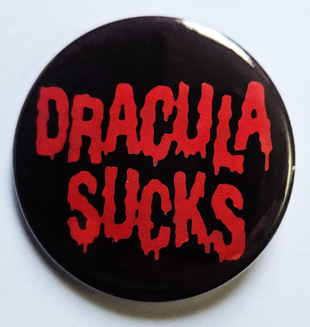 1.25 pinback button with black background and message "DRACULA SUCKS" in drippy blood red font