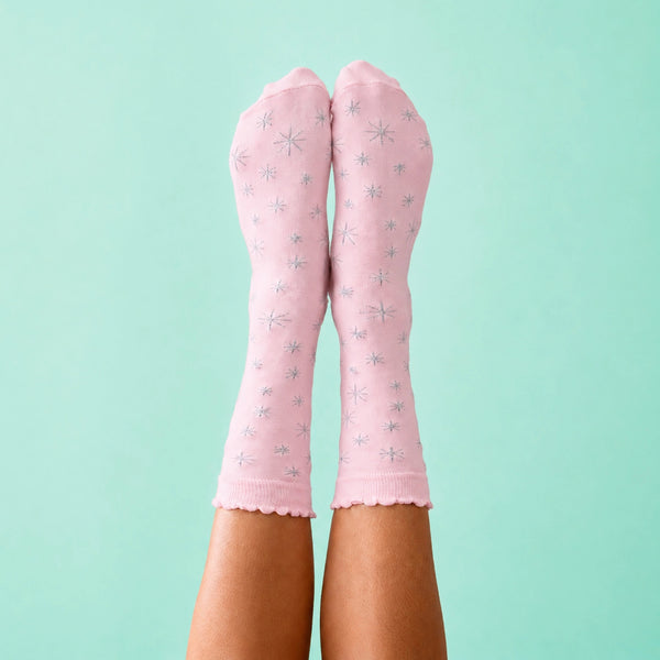 light pink unisex cotton crew socks with silver lurex star patterns shown worn on a blue background