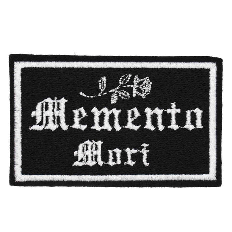 black felt embroidered patch with a white border and "Memento Mori" written in white Olde English script below a white flower