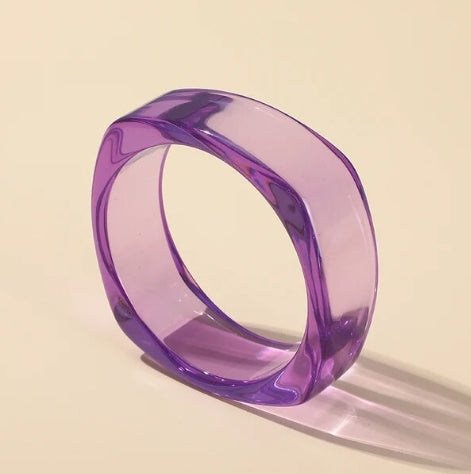 A rounded square bangle in bright purple lucite shown on its side 