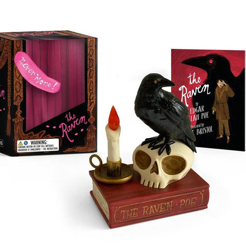 Decorative figurine with a crow on a skull, candle, and book titled 'The Raven' by Edgar Allan Poe, with packaging in the background.