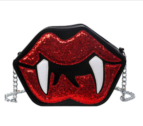 Black faux leather purse with red glittery lips and white fangs and chain strap on a white background