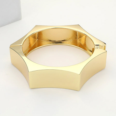 shiny gold metal hexagon shaped hinged bangle. Shown on its side