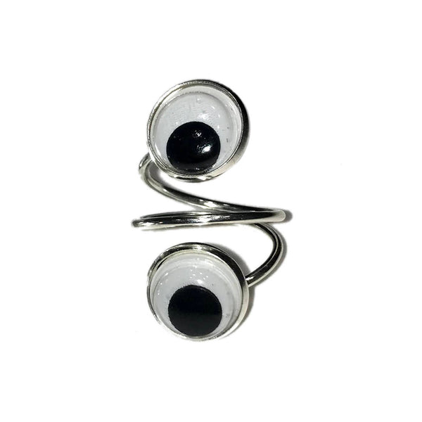 Silver metal spiral-shaped ring with face of ring adorned with two plastic black and white googly eyes. Shown flat from top