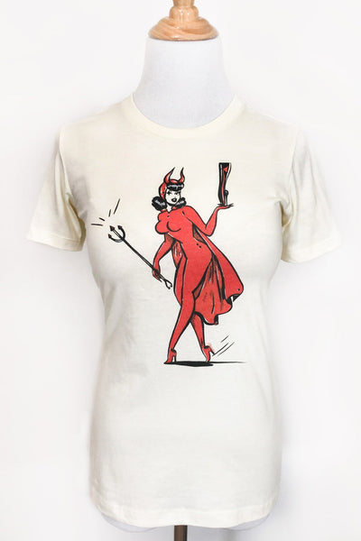 ivory t-shirt with printed illustration of vintage style pinup wearing devil costume with horns and cape, holding a black trident in one hand and a fetish-style high heeled boot in the other. Shown from front on dress form