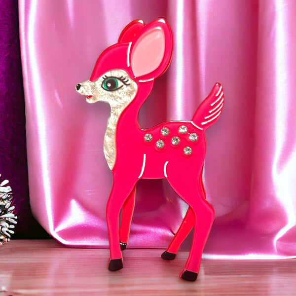 layered acrylic resin brooch of a hot pink deer with large blue eyes and inlaid silver rhinestones on its back. Shown on a hot pink background