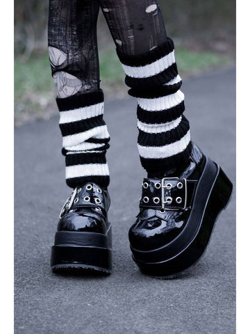 white and black ribbed striped leg warmers shown worn by model with ripped tights and black patent shoes