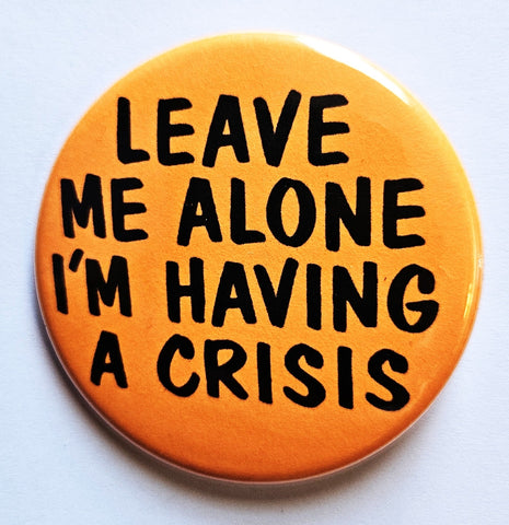 1.25” round pinback button with bright orange background and message “LEAVE ME ALONE I’M HAVING A CRISIS” in black lettering