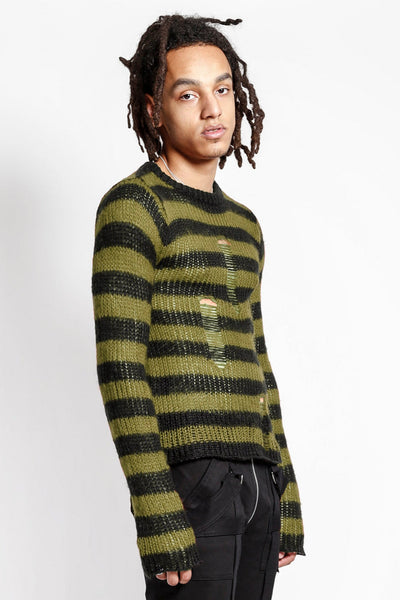male model wearing a green and black striped long sleeve sweater with distressed detail on the front of the body on a white background. Shown from the side
