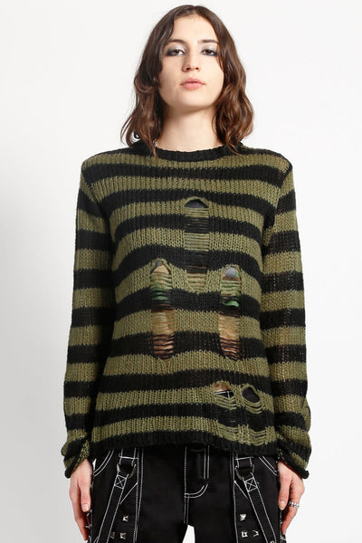 female model wearing a green and black striped long sleeve sweater with distressed detail on the front of the body on a white background