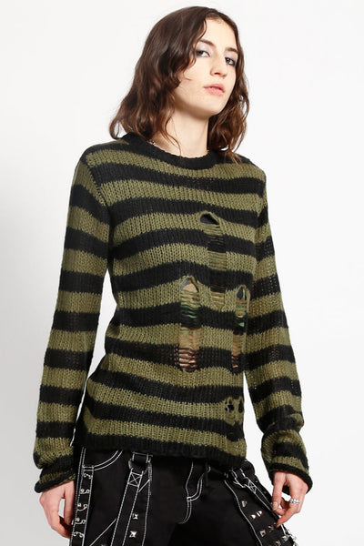 female model wearing a green and black striped long sleeve sweater with distressed detail on the front of the body on a white background. Shown from the side