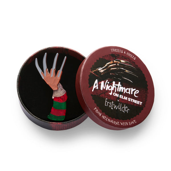 nightmare on elm street freddy krueger character's glove and arm in red and green striped sweater layered acrylic resin brooch, shown in illustrated round box packaging