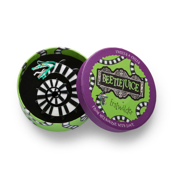 layered acrylic resin brooch of a coiled black and white striped Beetlejuice Sandworm, shown in illustrated round box packaging