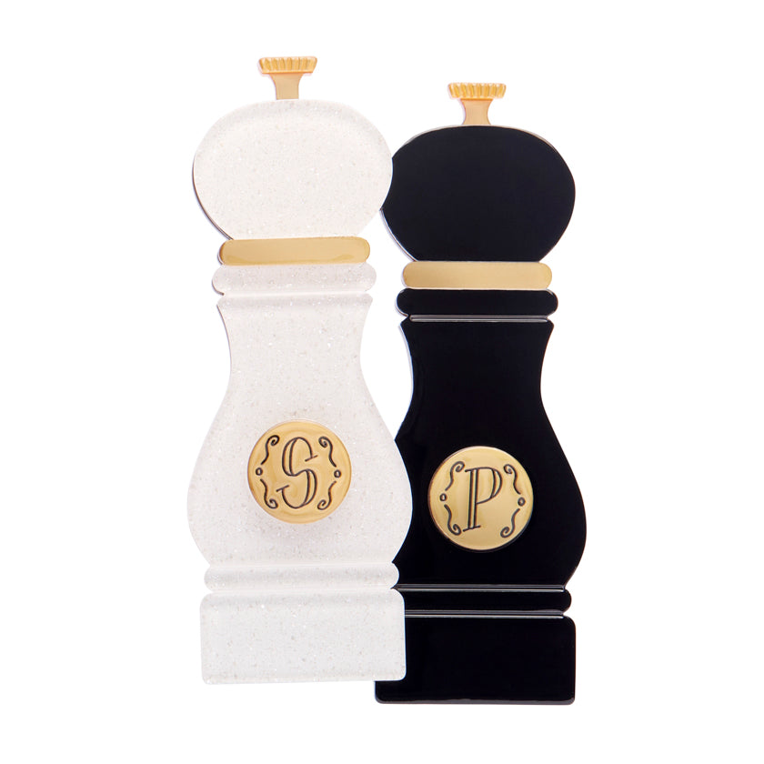 White and black layered acrylic resin pepper grinder set brooch with gold monogram on a white background