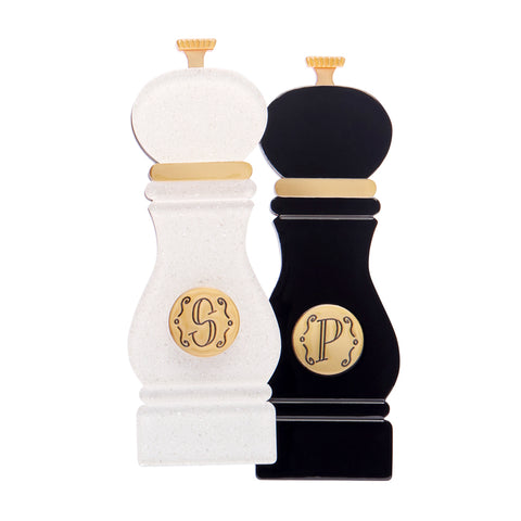 White and black layered acrylic resin pepper grinder set brooch with gold monogram on a white background