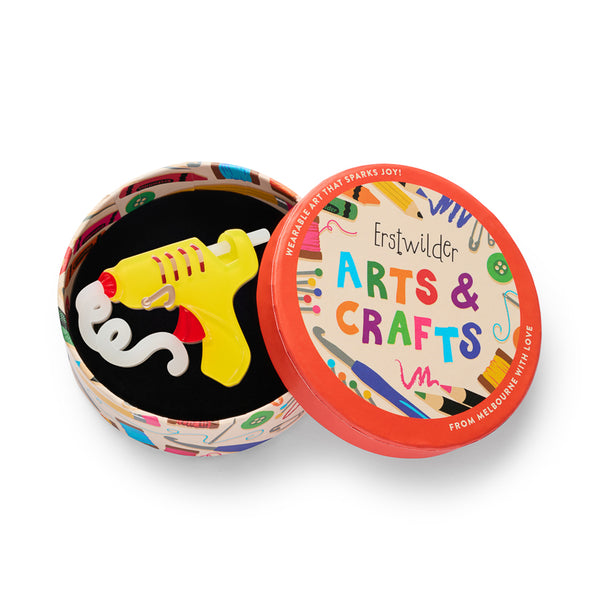 yellow and red hot glue gun shaped acrylic resin brooch, shown in illustrated round box packaging