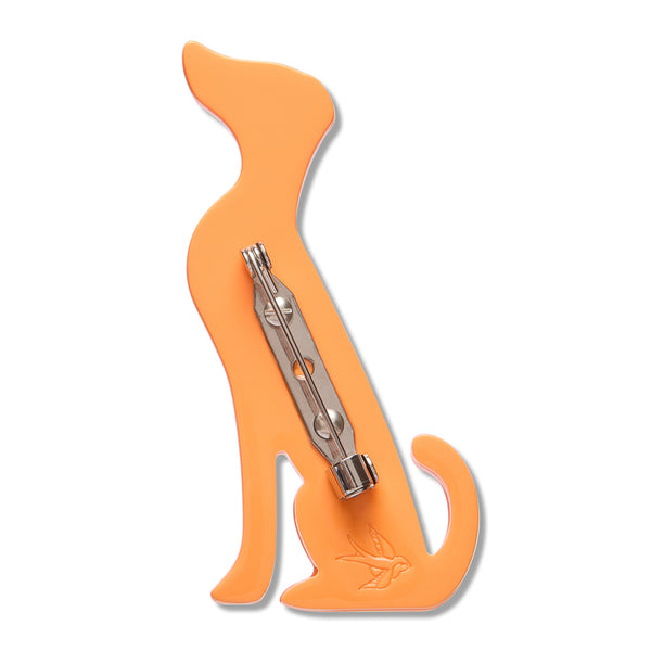 An orange dog-shaped brooch with a silver metal pin on the back, shown against a plain white background.