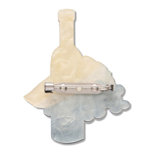 back view of a creamy white crylic resin brooch in the shape of a wine bottle with grapes and cheese