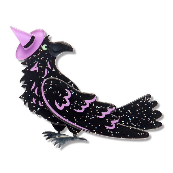 A glitter black raven acrylic resin brooch with a lavender witch hat and wing accents.